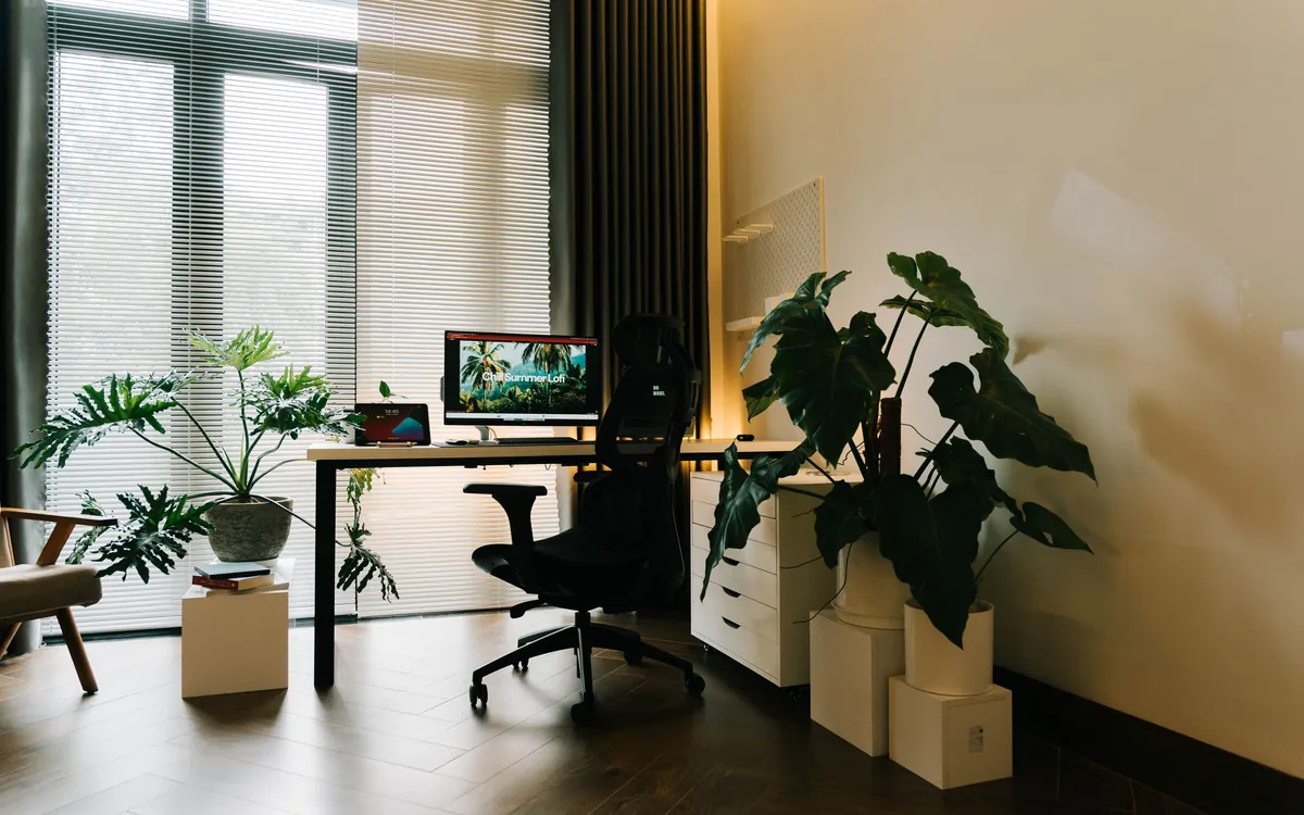 Ein helles Arbeitszimmer mit PC am Schreibtisch und großen Pflanzen